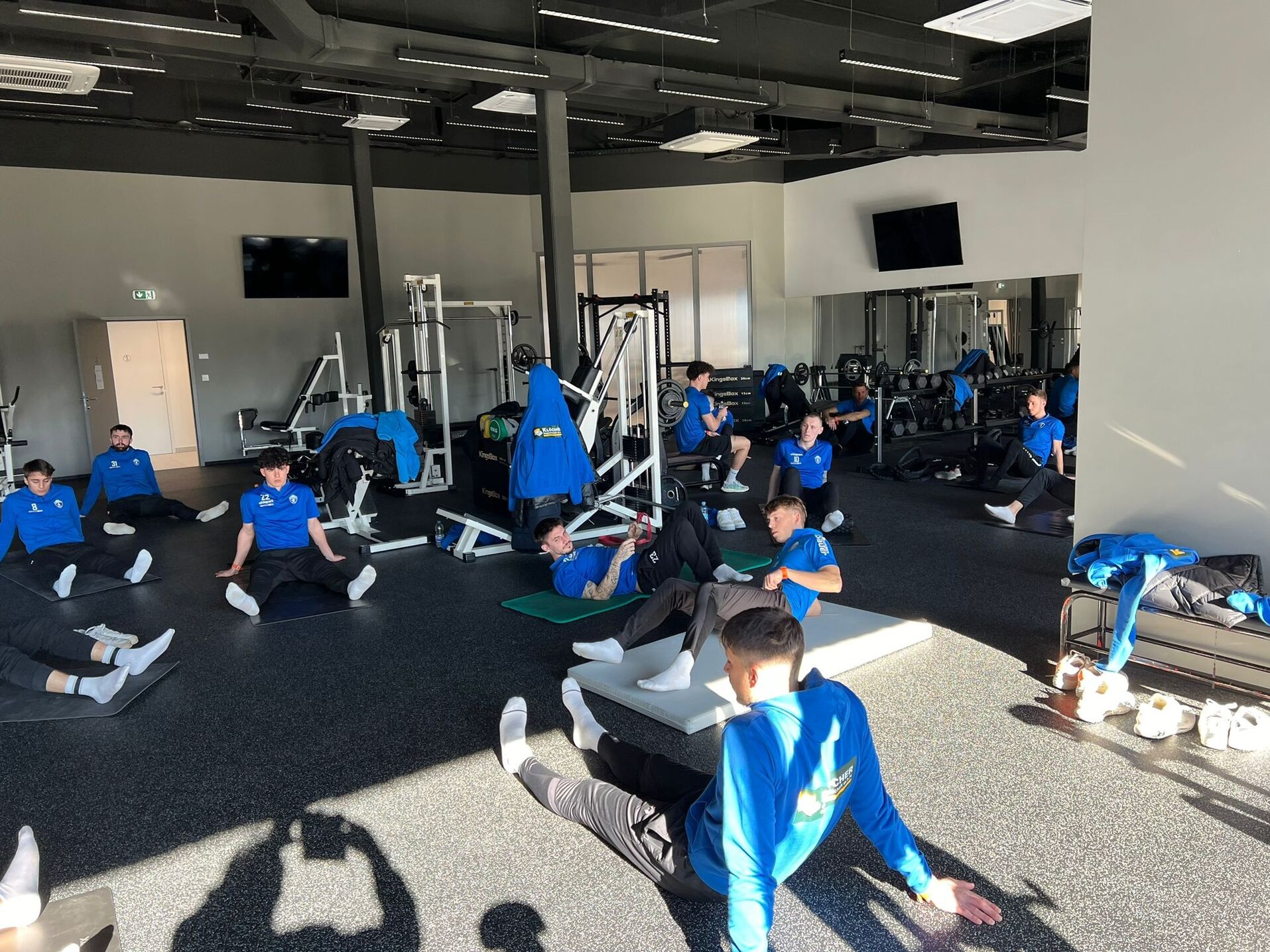 Jugend-Fußballmannschaft beim Dehnen im Fitnessstudio, Vorbereitung und Training für Spiele, Teamwork und Fitness.