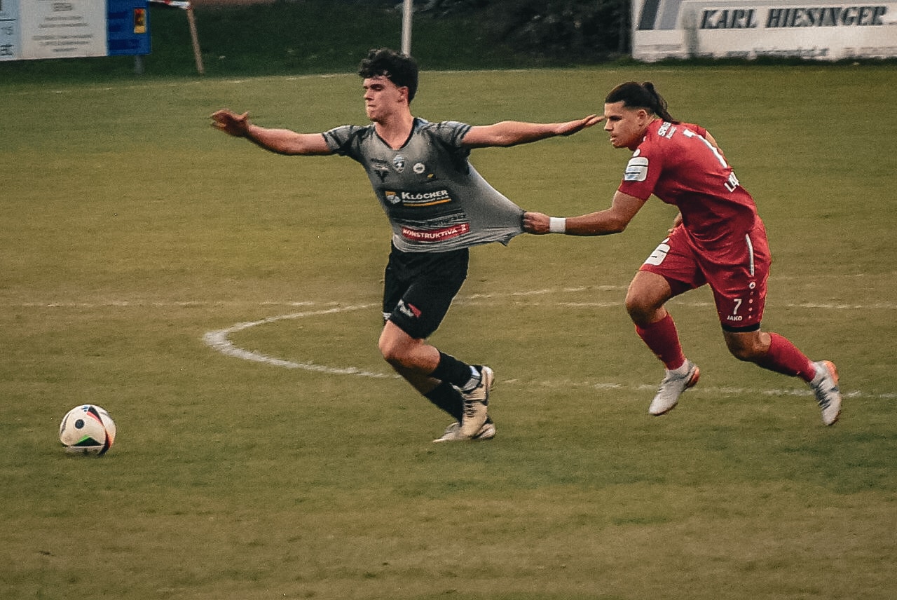 Fußballspieler in action, zieht Trikot des Gegners auf dem Spielfeld. Spannung im Wettkampf.