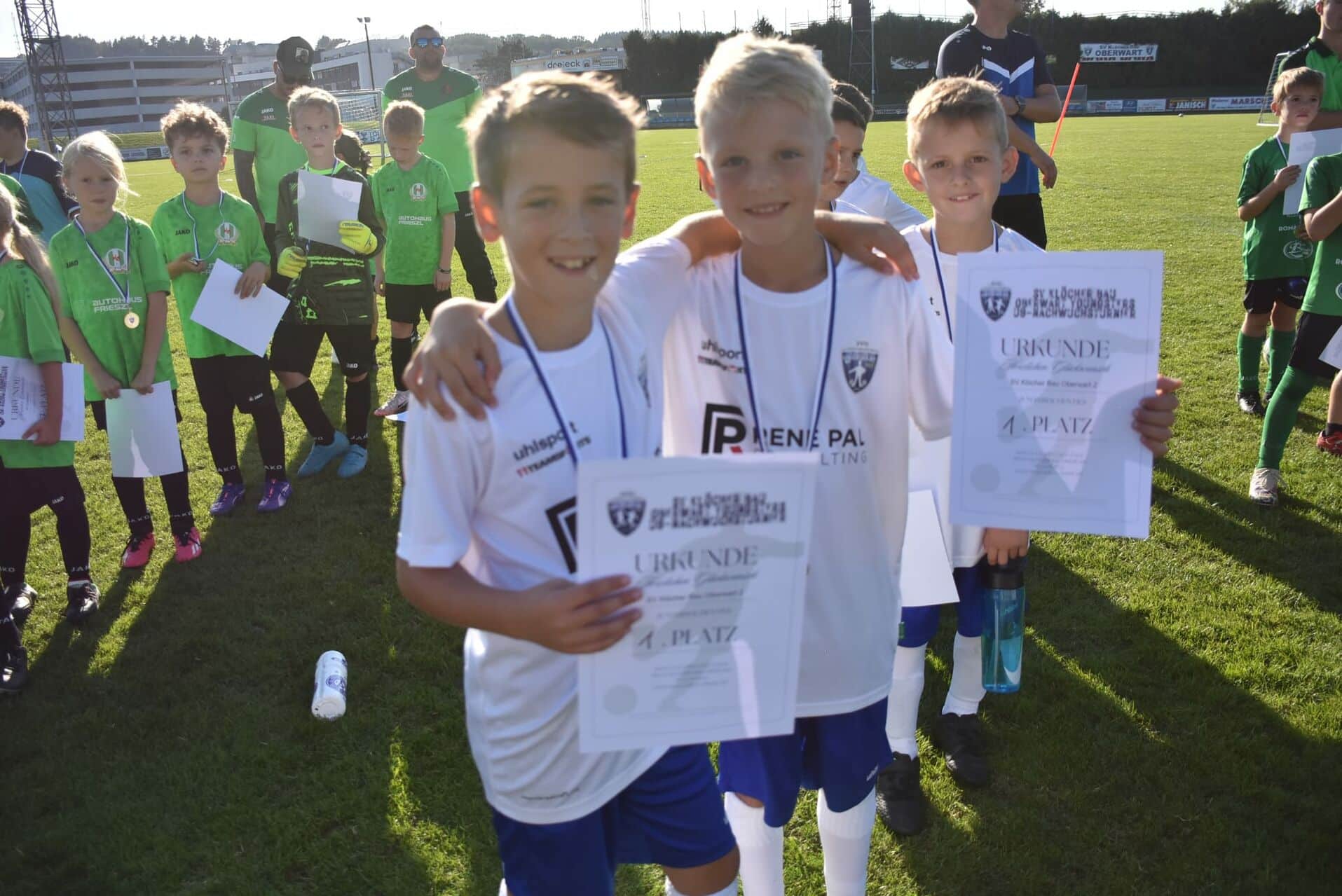 Kinder beim Fußballturnier halten Urkunden und Medaillen, glücklich über ihren Sieg auf dem Sportplatz.