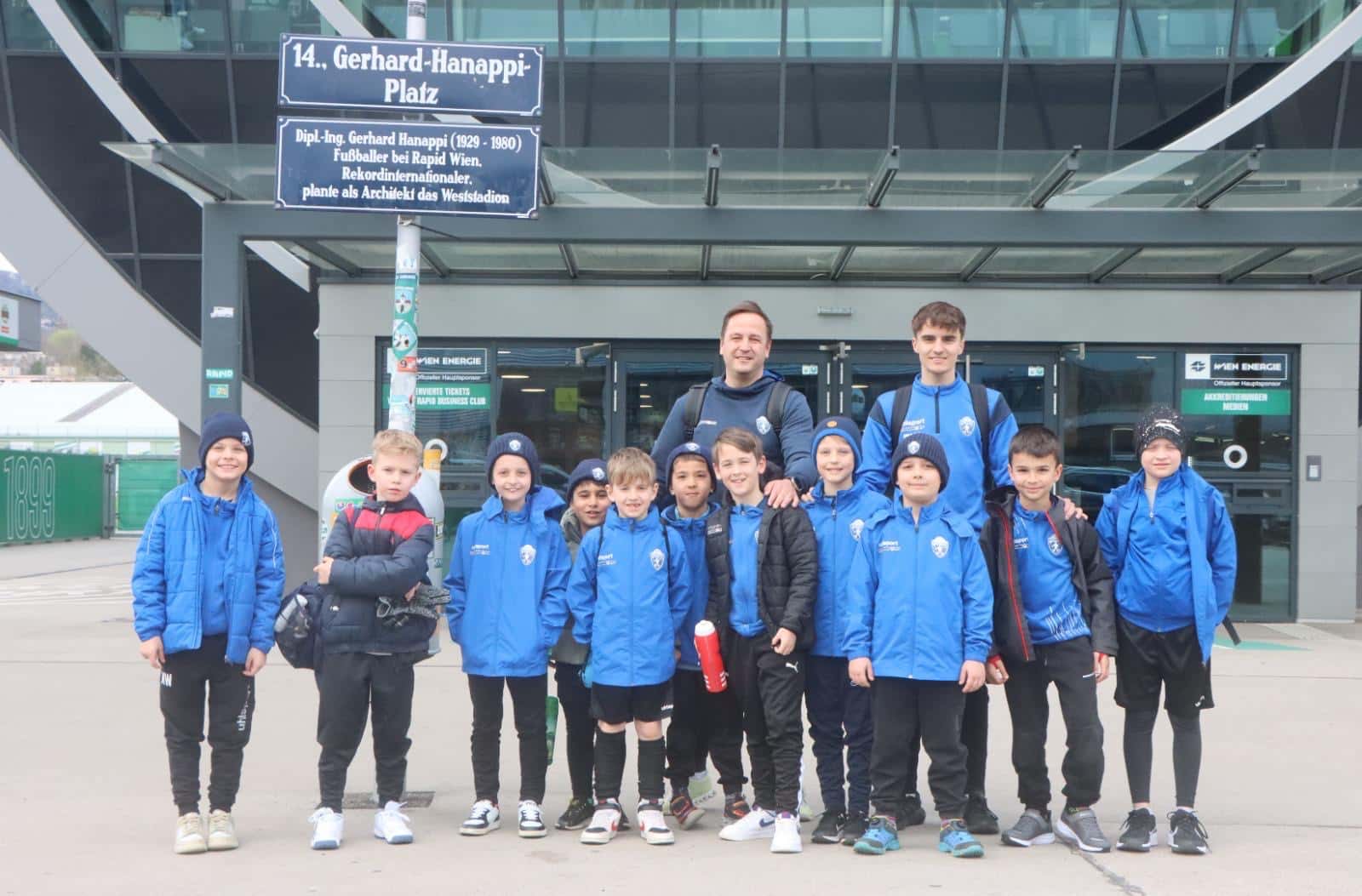 Kindergruppe in blauen Jacken vor dem Eingang des Gerhard-Hanappi-Platzes, Heimat von Rapid Wien.