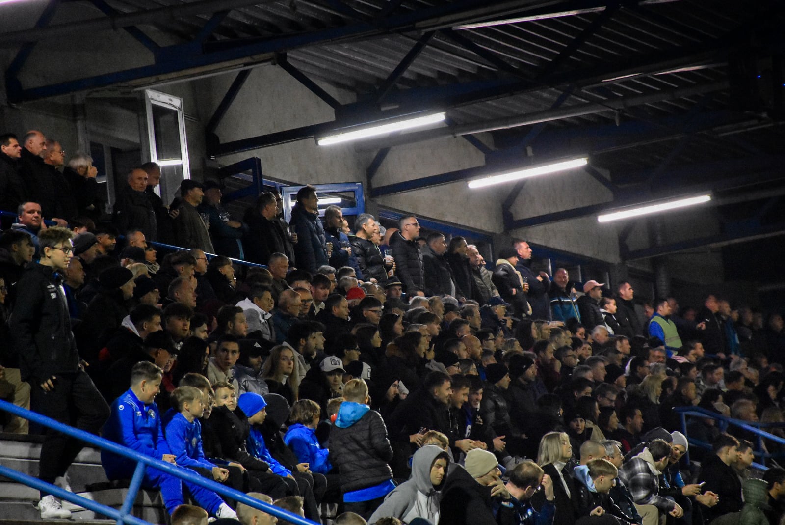 Zuschauer im Stadion jubeln bei einem Fußballspiel, gefüllte Tribüne mit begeisterten Fans.