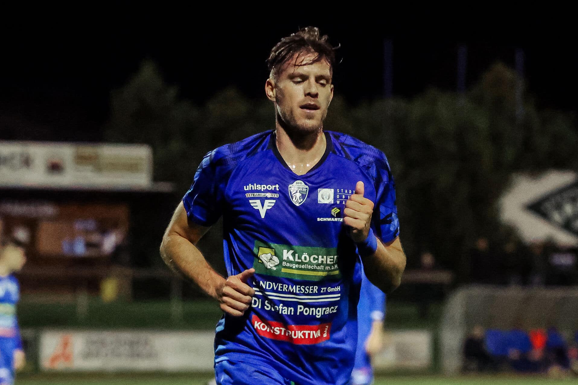 Fußballspieler in blauem Trikot läuft während eines Nachtspiels auf dem Spielfeld.