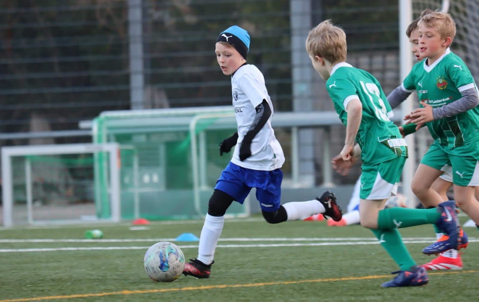 Kinder spielen Fußball auf dem Feld, konzentriert beim Wettkampf im Freien bei kaltem Wetter.