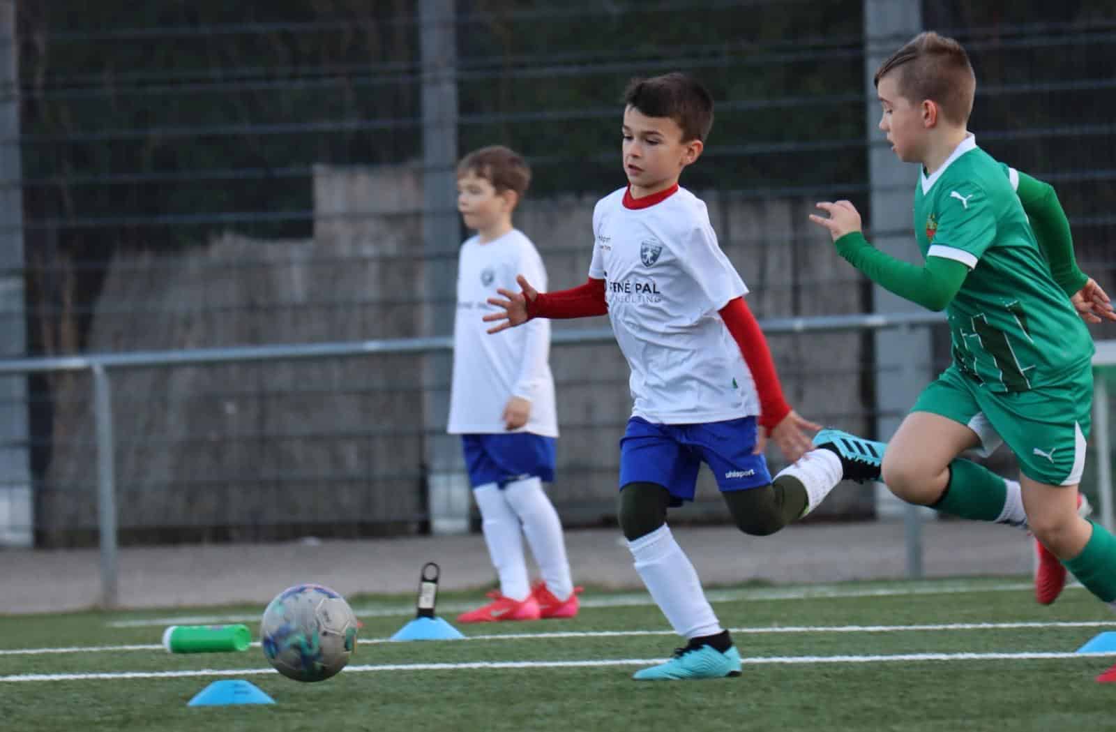 Junge Fußballer im Wettlauf um den Ball auf einem Fußballfeld in Aktion, Fokus auf Teamgeist und Sportlichkeit.