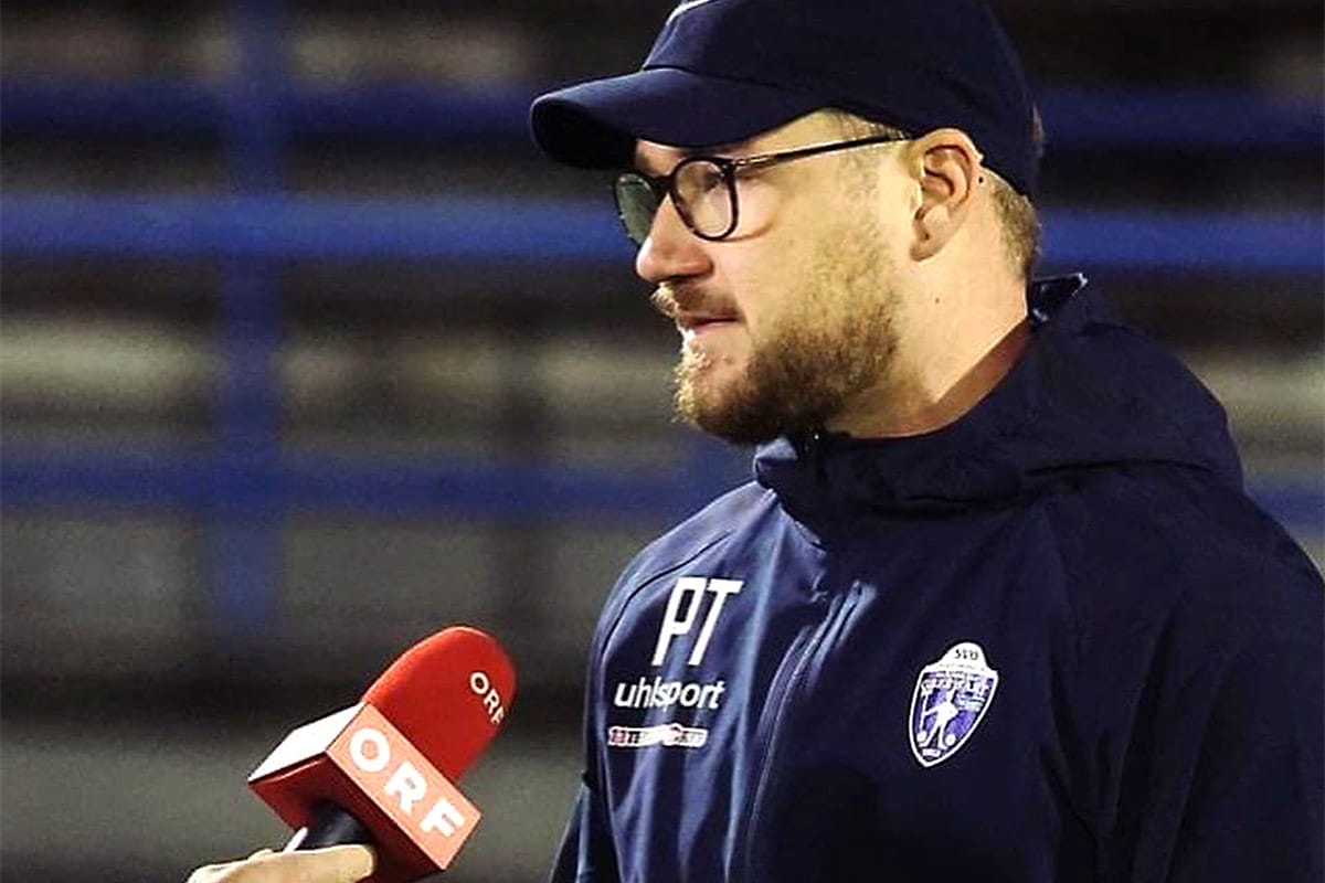 Person mit Brille gibt Interview für ORF, trägt Vereinsjacke und Cap, seitliches Profil, Sportkontext.