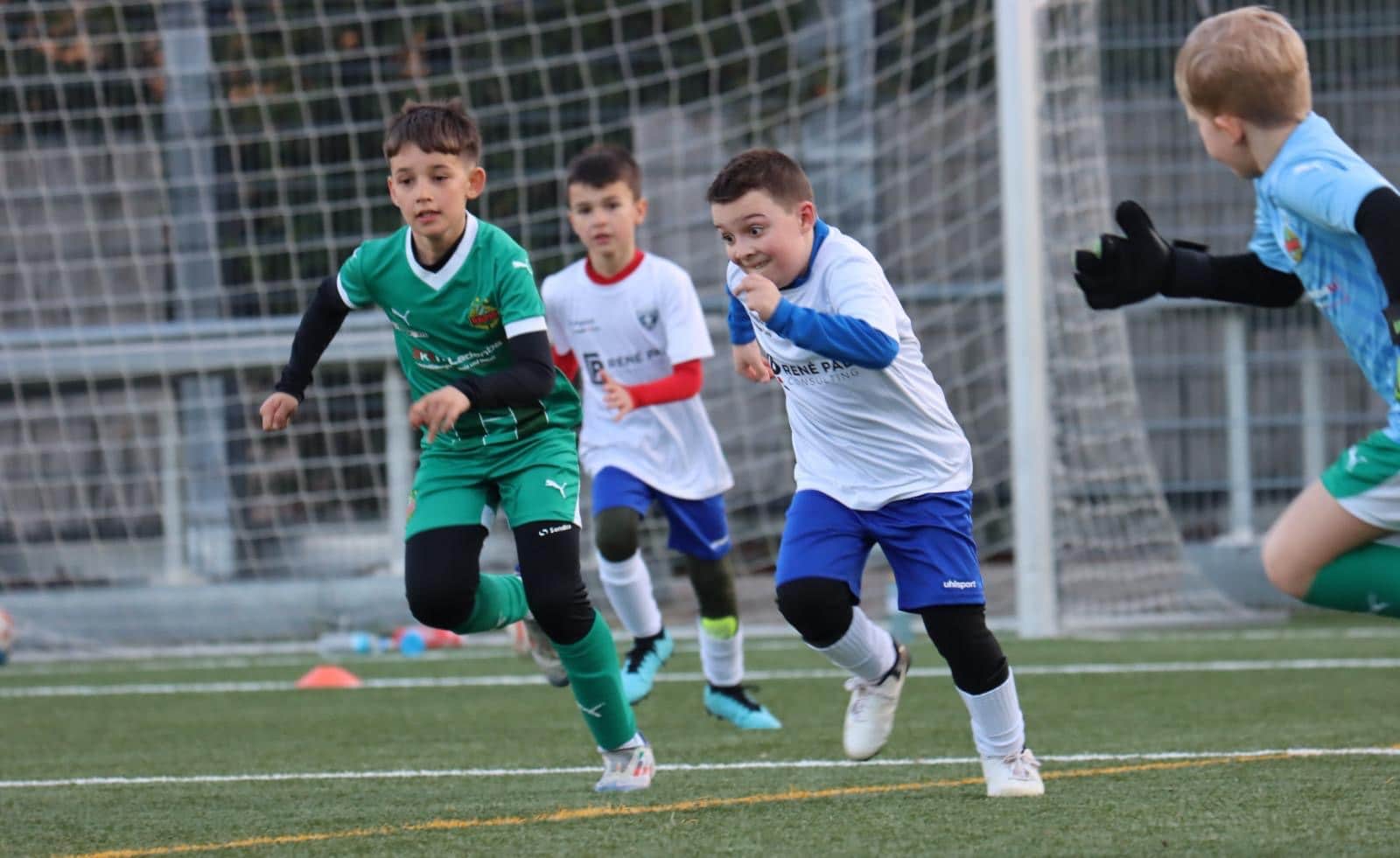 Kinder beim Fußballspiel auf dem Spielfeld, voller Einsatz und Spaß im Wettkampf.