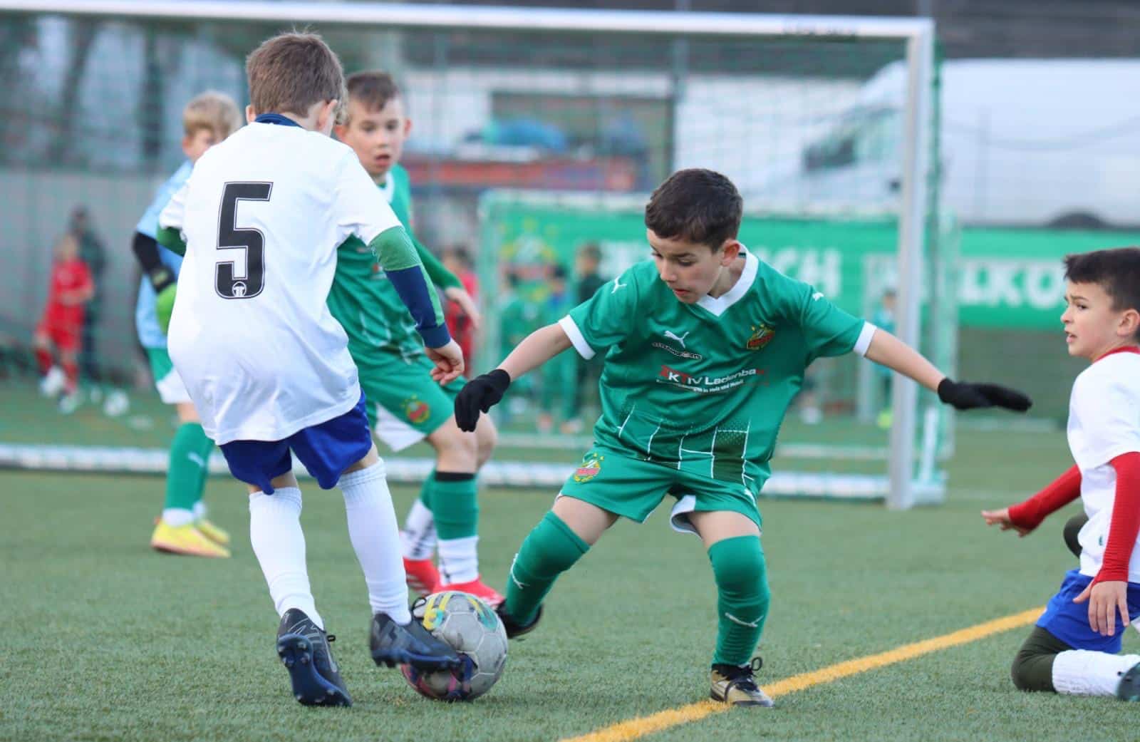 Kinder beim Fußballspiel auf dem Spielfeld, zwei Jungen in Aktion mit dem Ball, Wettkampf und Teamgeist.