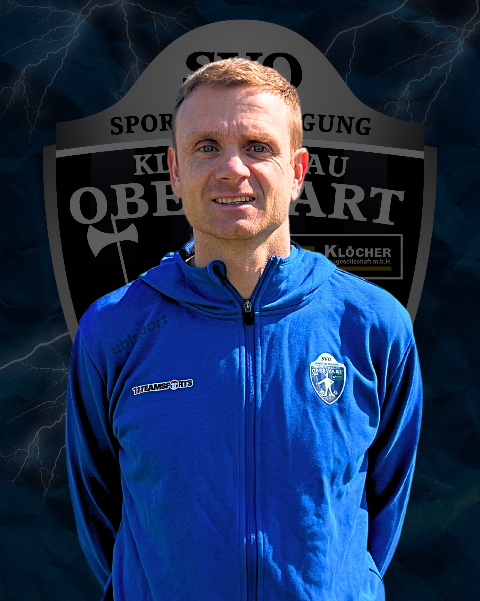 Ein Trainer in blauer Jacke vor dem Logo des SV Oberwart auf einem dunklen, blitzdurchzogenen Hintergrund.