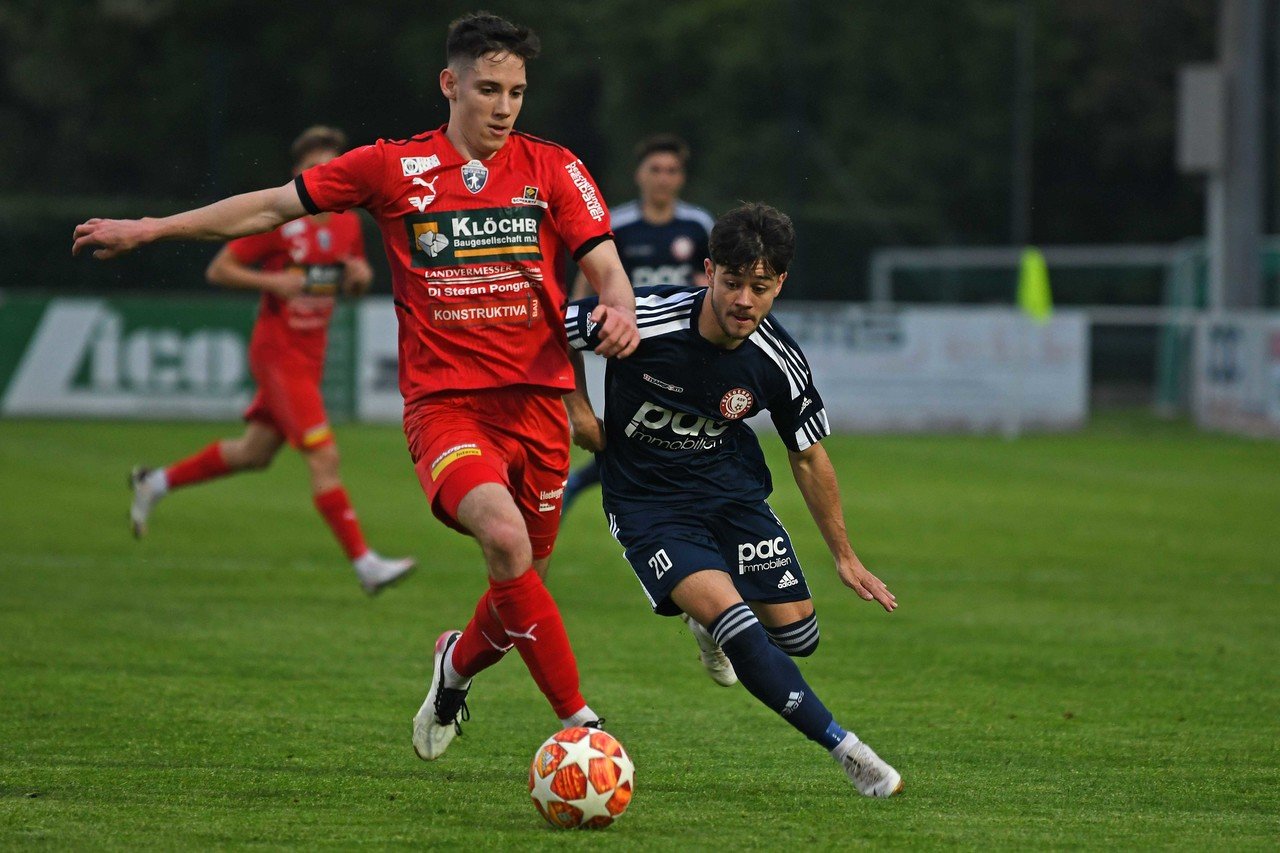 Zwei Fußballspieler im Duell um den Ball während eines Spiels auf dem Rasen.