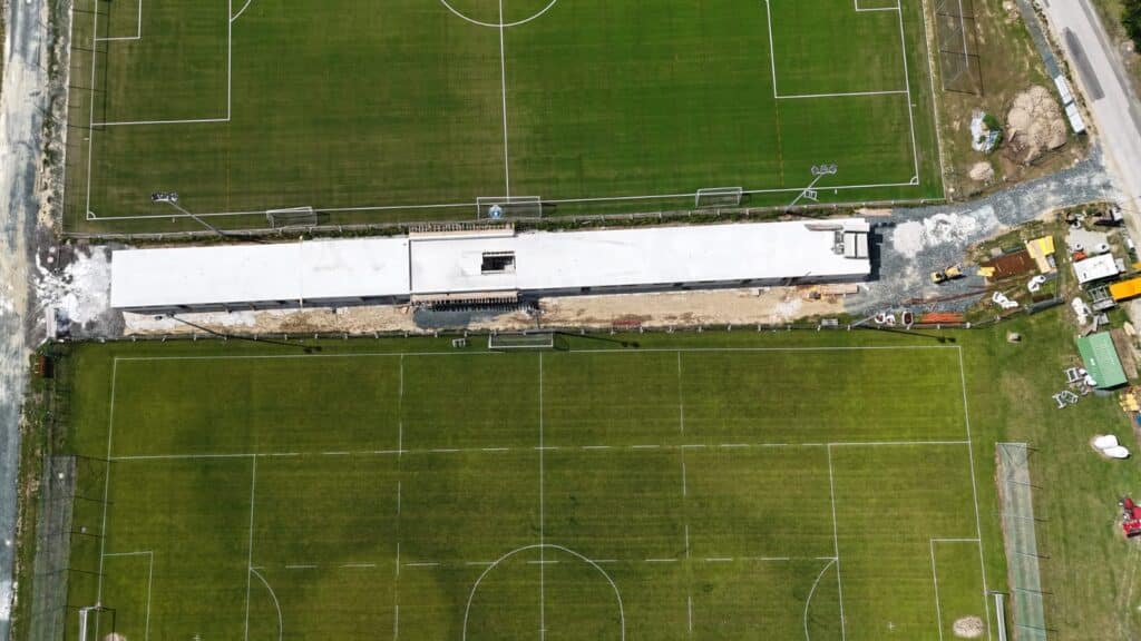Luftaufnahme von zwei nebeneinanderliegenden Fußballfeldern mit Bauarbeiten in der Mitte.