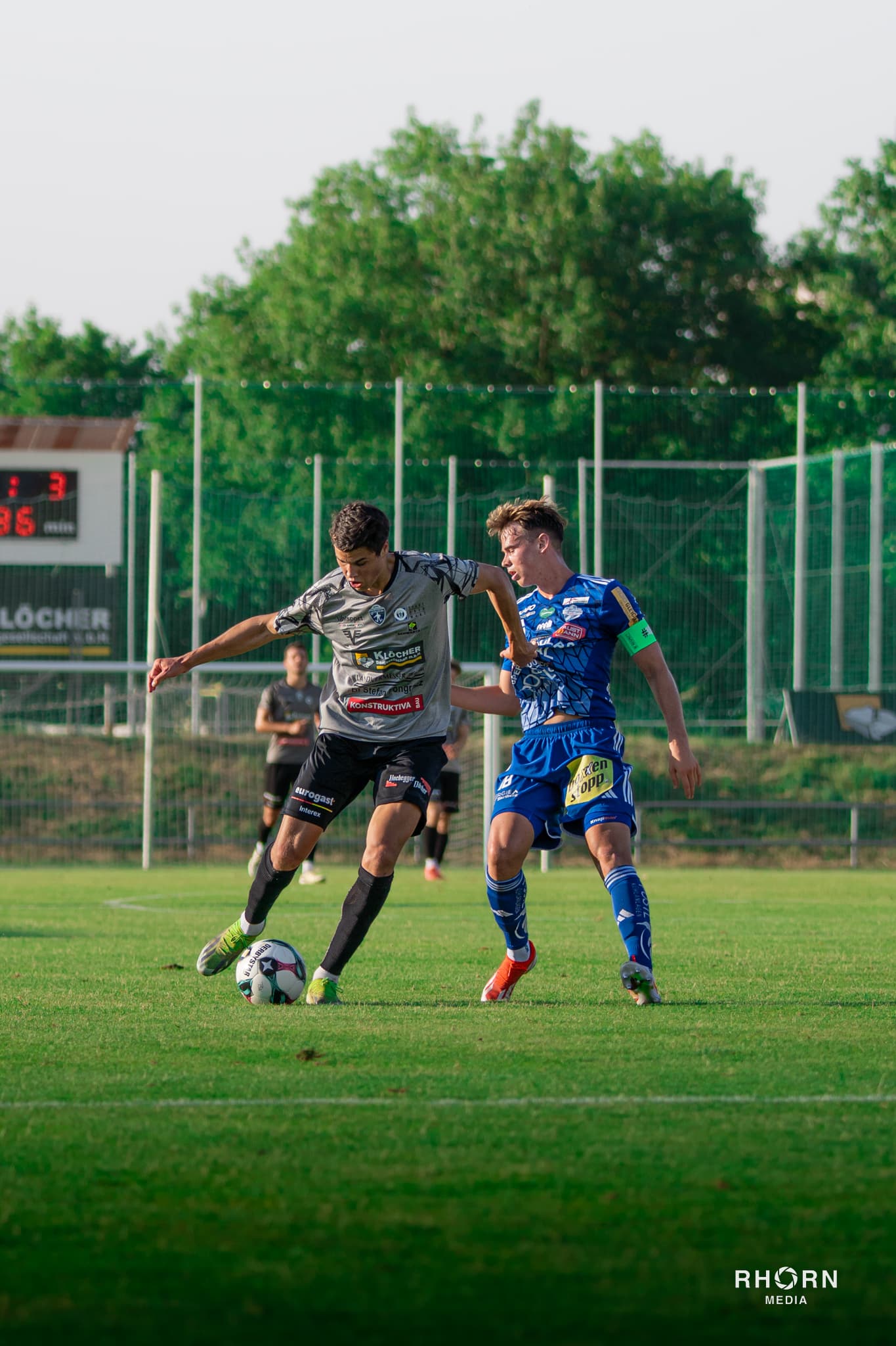 Zwei Fußballspieler im intensiven Zweikampf auf dem Spielfeld während eines spannenden Matches.