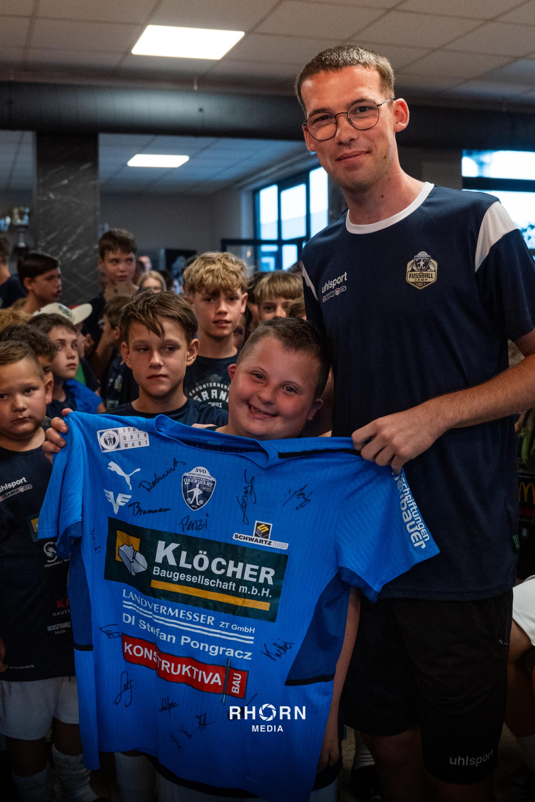 Kinder jubeln mit signiertem Fußballtrikot, unvergesslicher Moment bei einem Sportevent.