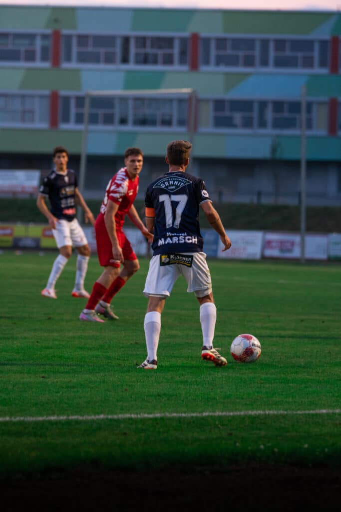 Fußballspiel im Freien, Spieler in Aktion, bereit für Torangriff, konzentrierte Spannung auf dem Spielfeld.