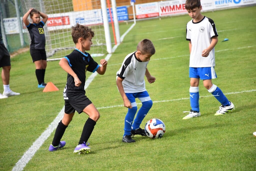 Kinder beim Fußballtraining auf dem Rasen, üben Dribbling und Teamarbeit in sportlicher Atmosphäre.